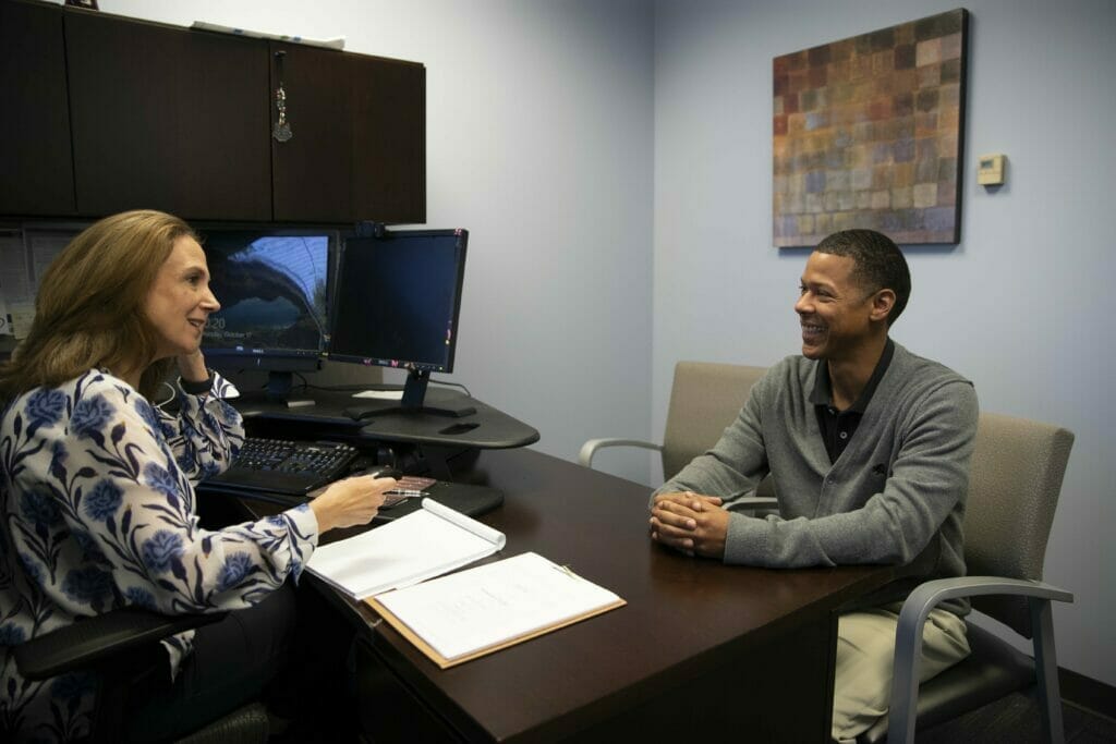 Woman providing financial counseling to a man at a desk in an office.