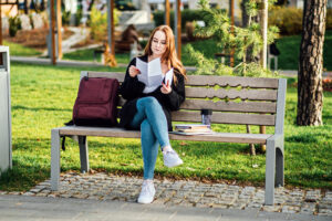 A woman sitting on a bench reading a document.